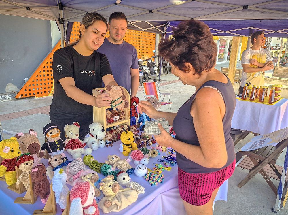 Evento passa a ser realizado na Praça Professora Marília Soares, reunindo mais de 40 expositores de artesanato, gastronomia autoral e atrações culturais. A Feira de Artesanato e Economia Criativa de Navegantes (FEIRARTE) ganha um novo endereço a partir deste domingo, 20 de setembro. O evento passa a ocupar a Praça Professora Marília Soares, localizada na Praia do Gravatá, consolidando o espaço como um ponto de encontro entre moradores, leitores e visitantes da região. A feira será realizada semanalmente, todos os domingos, das 14h às 18h30. O encontro reúne cerca de 44 expositores locais, destacando a produção autoral e o trabalho de pequenos empreendedores do município. Variedade e produção autoral Quem passar pelo local encontrará uma ampla diversidade de produtos feitos à mão. A feira contempla desde itens de decoração e casa — como cerâmicas, luminárias e almofadas — até peças de moda autoral, bijuterias e acessórios em crochê e tricô. O segmento de aromas e bem-estar estará presente com sabonetes naturais e velas aromáticas. O público também poderá adquirir peças de papelaria artesanal, brinquedos colecionáveis em biscuit e amigurumis, além de opções da gastronomia local, incluindo pães, geleias, doces e bolos caseiros. Incentivo à cultura e economia local Além da comercialização de produtos, a FEIRARTE integra uma programação com atrações artísticas para o público de todas as idades. A transferência para a Praia do Gravatá visa ampliar a visibilidade do artesanato local em uma área de grande circulação, estimulando a economia criativa e a geração de renda no município. Serviço Evento: FEIRARTE – Feira de Artesanato e Economia Criativa Data: Todos os domingos (início em 20 de setembro) Horário: Das 14h às 18h30 Local: Praça Professora Marília Soares – Praia do Gravatá, Navegantes Observação: Em caso de chuva ou condições climáticas adversas, a programação será transferida para o domingo seguinte.