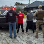 Operação conjunta das polícias Civil e Militar prende mandante de duplo homicídio e apreende armas e drogas Ação realizada na manhã desta quinta-feira (8) cumpriu mandado de prisão de suspeito de mandar matar casal no bairro Nossa Senhora das Graças, em Navegantes. Um segundo homem foi preso em flagrante no Distrito dos Kaetés, em Camboriú. Na manhã desta quinta-feira (8), uma operação conjunta entre a Polícia Civil (Delegacia de Navegantes) e a Polícia Militar (Agência de Inteligência e Tático do 25º BPM, com apoio do Tático do 12º BPM) cumpriu o mandado de prisão do mandante do duplo homicídio que vitimou Felipe Silva Santos e Fernanda Xisto Furtado. Durante as diligências, as equipes também cumpriram um mandado de busca e apreensão em um imóvel rural situado no Distrito dos Kaetés, no município de Camboriú. No local, um jovem de 21 anos foi preso em flagrante. Além de possuir dois mandados de prisão em aberto por homicídio, ele foi autuado por tráfico de drogas e porte ilegal de arma de fogo de uso restrito. Na propriedade rural, as forças de segurança apreenderam uma vasta quantidade de material ilícito: Armamento e munições: 1 pistola Taurus G2C calibre 9mm, 82 munições calibre 9mm, munições nos calibres .380 (1 un.), .38 (3 un.) e .40 (1 un.), além de 1 kit roni (dispositivo utilizado para converter pistolas em armas longas). Entorpecentes: Cerca de 1 kg de maconha, comprimidos de ecstasy e porções de cocaína. Eletrônicos: 6 aparelhos celulares. O Crime em Navegantes As vítimas Felipe Silva Santos e Fernanda Xisto Furtado foram assassinadas com dez disparos de pistola na madrugada do dia 2 de setembro de 2026, enquanto dormiam em uma residência no bairro Nossa Senhora das Graças, em Navegantes. Segundo a investigação, o crime foi motivado por uma desavença comercial e interpessoal entre Felipe e o mandante, seu ex-sócio e ex-amigo. Imagens de câmeras de monitoramento registradas na data do crime mostram que dois executores chegaram ao local em uma motocicleta, invadiram o imóvel e efetuaram os disparos contra o casal. Após a realização de todos os procedimentos cartorários na delegacia, os dois presos foram encaminhados ao Complexo Prisional do Vale do Itajaí, onde permanecem à disposição da Justiça.